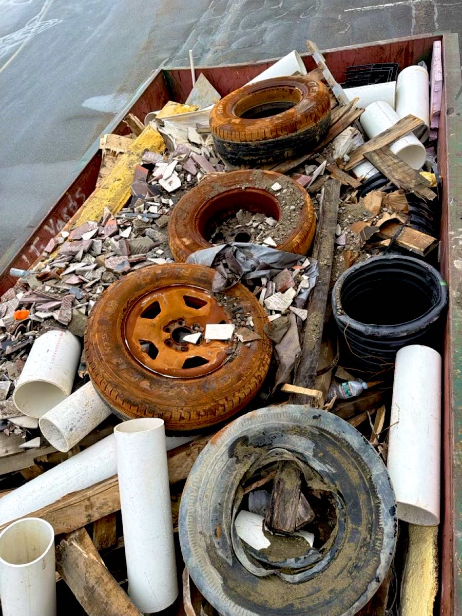Dumpster load with old tires mixed in with construction debris