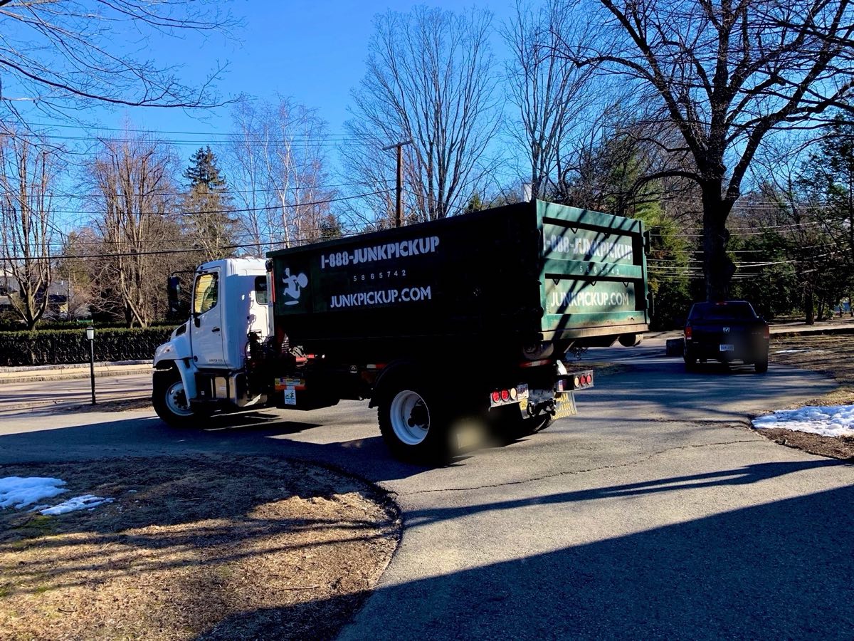 Roll-off truck delivering a dumpster into a home driveway