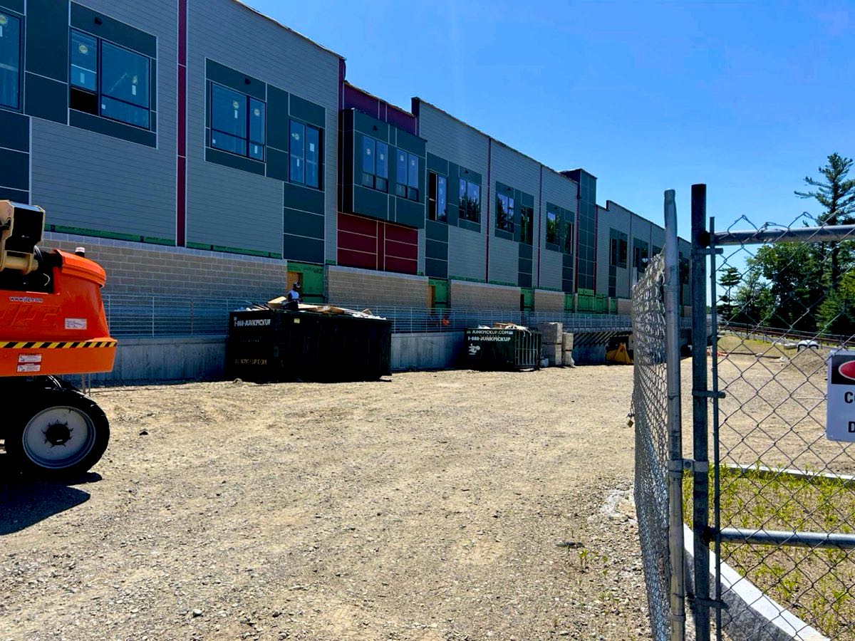 Two roll-off dumpsters beside a building at Sharon Commons in Sharon, MA